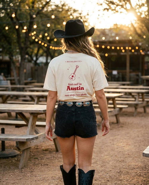Austin Bachelorette Oversized Tee in Ivory knotted with denim cutoffs, cowboy hat and boots