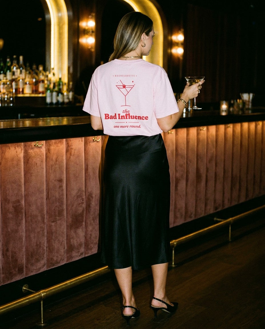 The Bad Influence Oversized Tee in Blossom with a black satin skirt at a cocktail bar