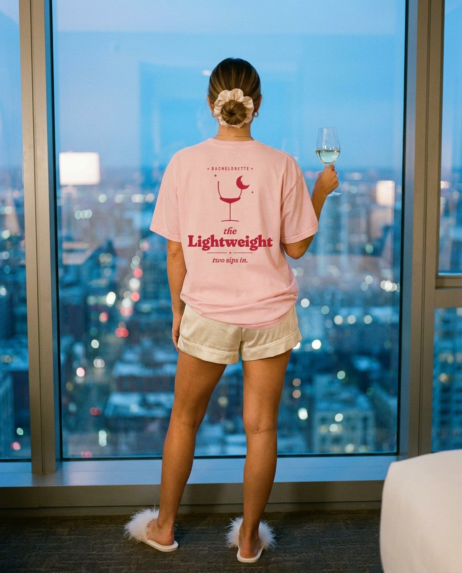 The Lightweight Oversized Tee in Blossom with silk pajama shorts by a hotel window